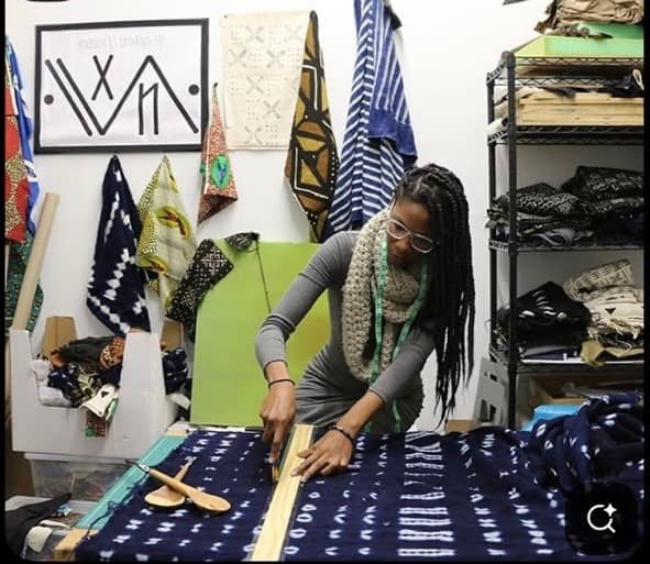 Créatrice découpant un tissu indigo dans son atelier